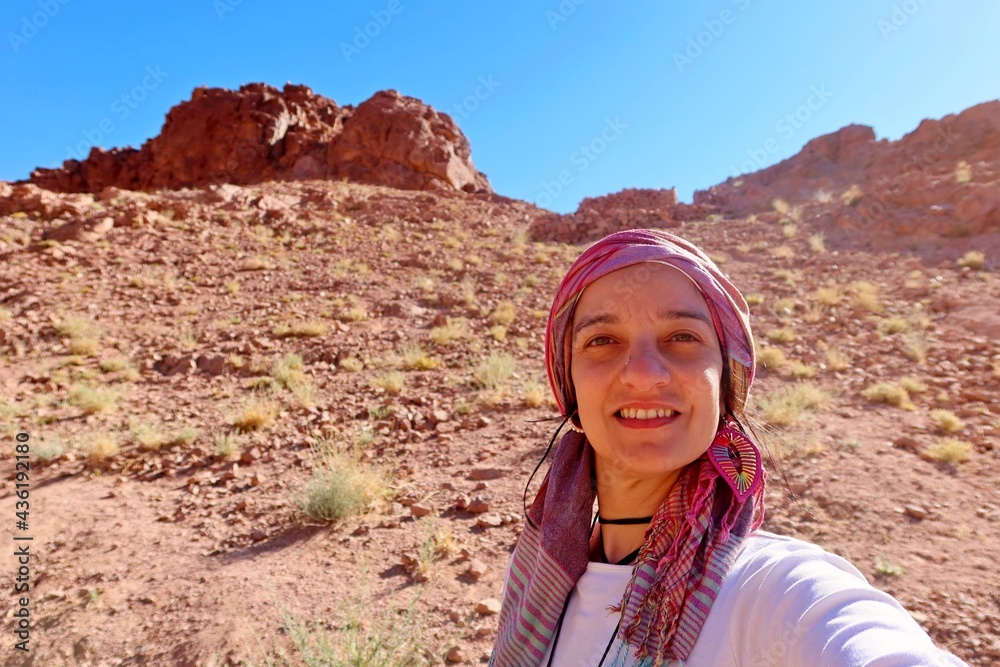 selfie of a hazel eyes young woman wearing a head cover in a hiking trip adventure in the middle of the mountains and valleys of saint Catherine in Sinai in Egypt