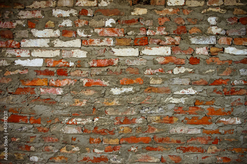 Old brick wall background. Red, orange, yellow and white bricks with gray seams
