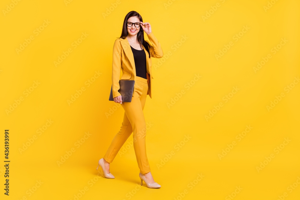Full length profile photo of nice young agent lady go with laptop wear yellow blazer trousers isolated on vivid color background Full length profile photo of nice young agent lady go with laptop wear yellow blazer trousers isolated on vivid color background