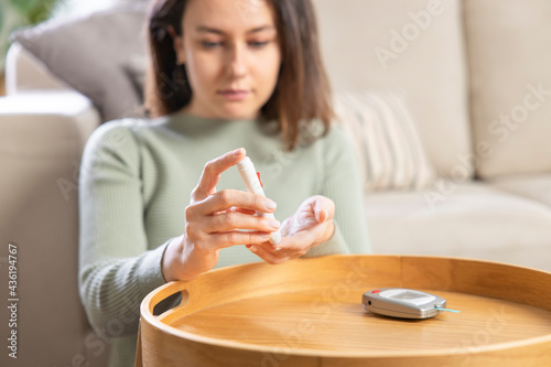 Young woman doing blood sugar test at home photo