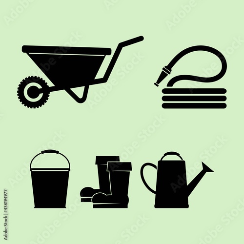 Set of vector illustrations of silhouettes of garden wheelbarrow, hose, rubber boots, bucket and watering can. Set of variety objects of gardening tools and accessories.