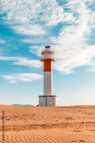  Fangar  lighthouse situated in Ebro Delta beach. Picture taked during a sunny day with clouds in a blue sky.