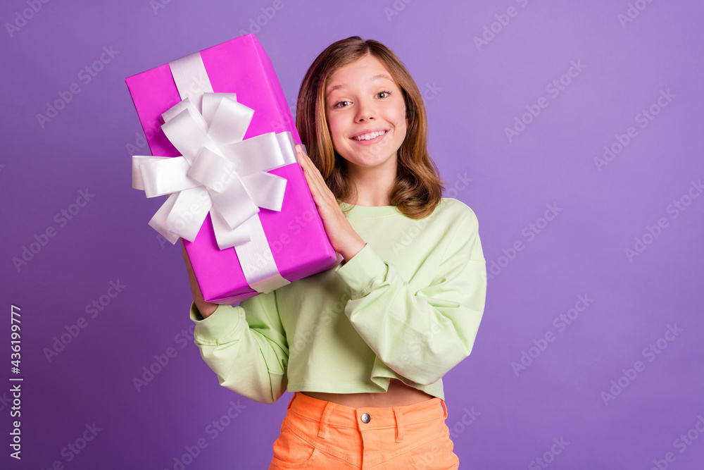 Photo of young cheerful girl happy positive smile hold gift box party holiday isolated over violet color background Photo of young cheerful girl happy positive smile hold gift box party holiday isolated over violet color background