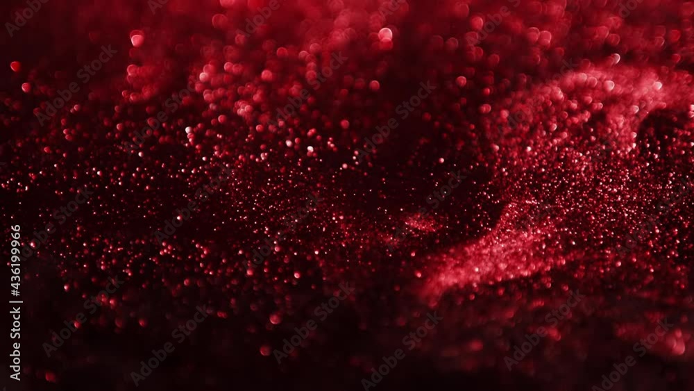 Red glitter background in slow motion. Cinematic red particles on black background