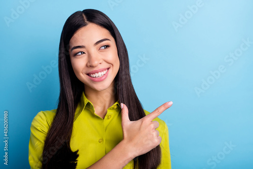 Photo of young woman happy positive smile look indicate finger empty space select suggest promo isolated over blue color background