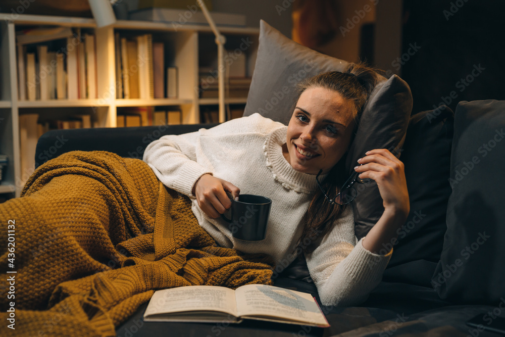 woman reading book at home. she is relaxing on a sofa at home woman reading book at home. she is relaxing on a sofa at home