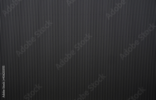 Black corrugated iron sheet used as a facade of a warehouse or factory. Texture of a seamless corrugated zinc sheet metal aluminum facade. Architecture. Metal texture.
