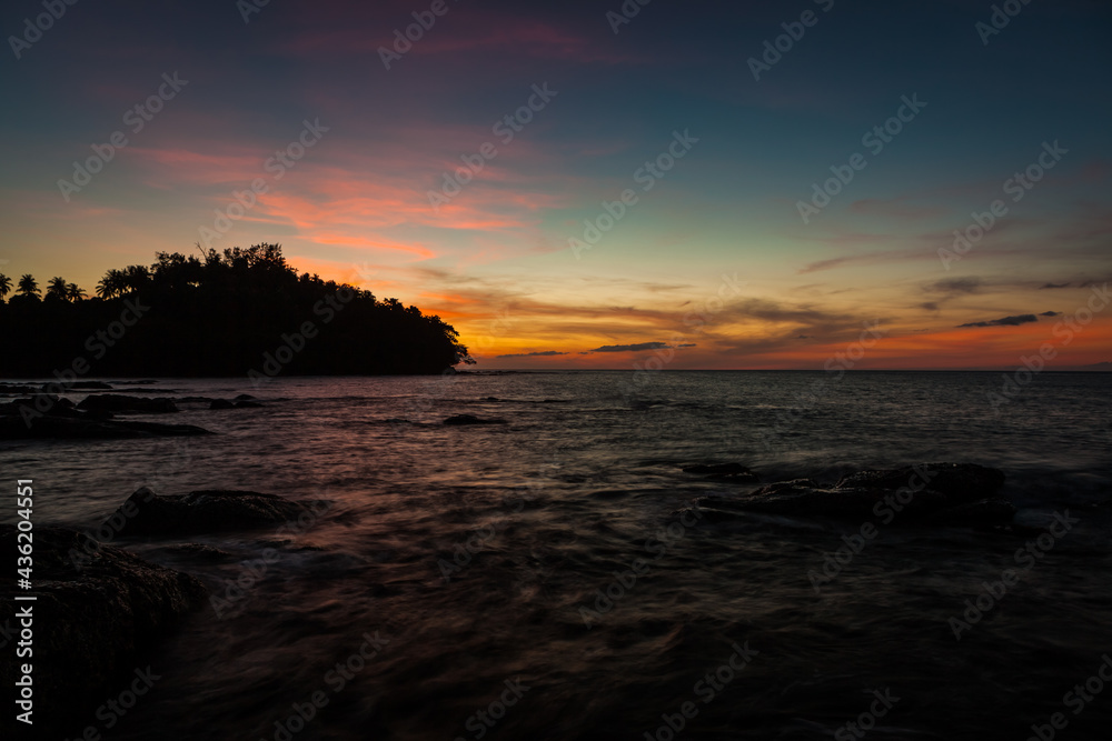 Obraz premium Vivid sunset sky waterscape and silhouette forest island