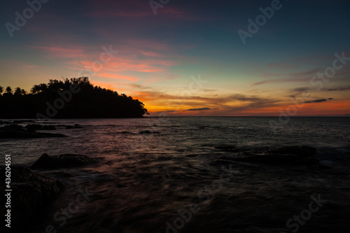 Vivid sunset sky waterscape and silhouette forest island