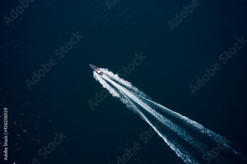 Drone view of a boat sailing. Top view of a white boat sailing to the blue sea. Large white boat fast movement on blue water aerial view. Motor performance boat in the sea. © Berg