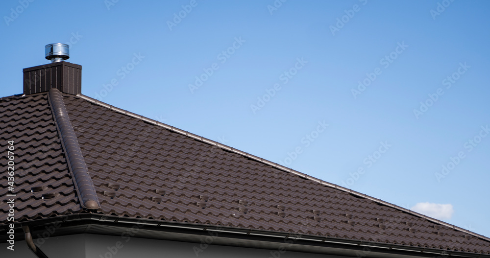 Brown corrugated metal profile roof installed on a modern house. The roof of corrugated sheet. Roofing of metal profile wavy shape. Modern roof made of metal. Metal roofing.