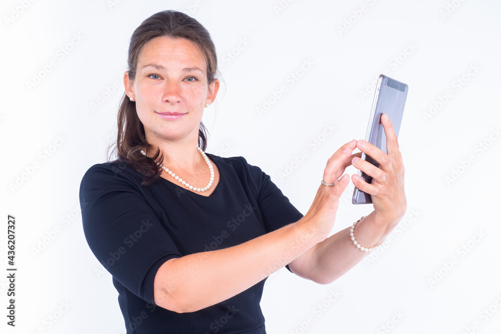 Woman with a tablet looks at camera. Smiling woman over white background. Businesswoman poses with an electronic tablet. Concept - she is using a business application. Business management application Woman with a tablet looks at camera. Smiling woman over white background. Businesswoman poses with an electronic tablet. Concept - she is using a business application. Business management application