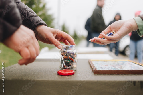 The hand putting used batteries into jar for recycling. Concept of collection and separating waste.
