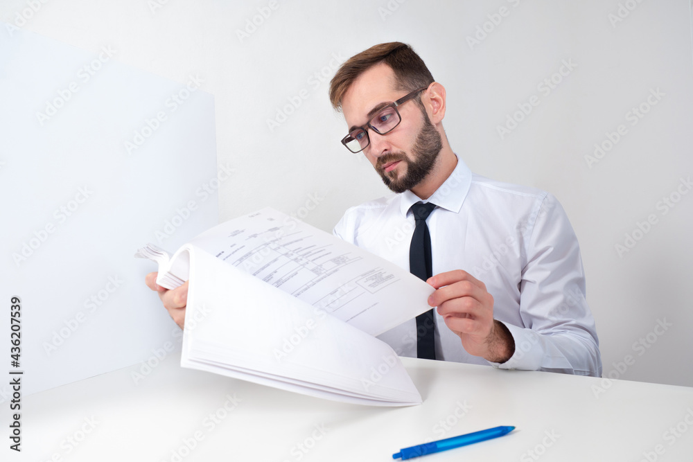 Lawyer is reading something. Documents in hands of a man. Lawyer is sitting on background of white paper. Concept - services of a law firm. He examines contract for correctness. Man checks contract Lawyer is reading something. Documents in hands of a man. Lawyer is sitting on background of white paper. Concept - services of a law firm. He examines contract for correctness. Man checks contract