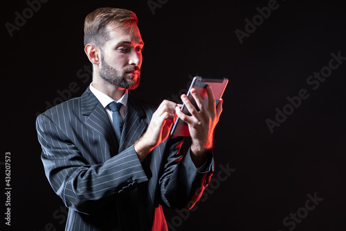 A man in a suit holds a tab...