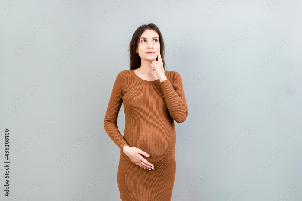 Pensive pregnant woman choosing name for baby on colored background. Dream and Happy Pregnant Woman Thinking Imagining Motherhood Life. Copy Space Pensive pregnant woman choosing name for baby on colored background. Dream and Happy Pregnant Woman Thinking Imagining Motherhood Life. Copy Space
