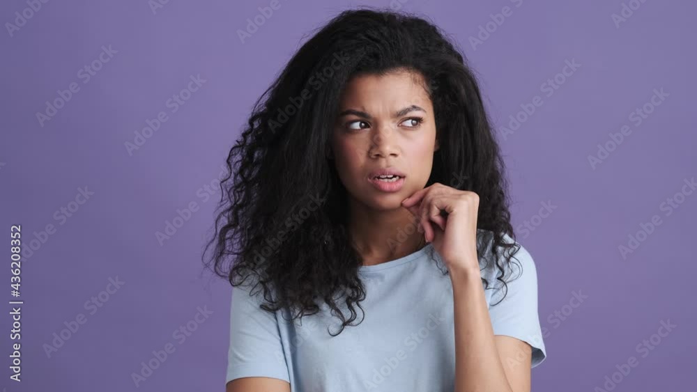 A brooding african woman in a t-shirt thinking about something and having an idea in a purple studio