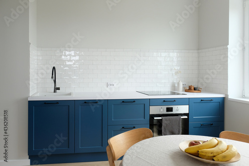 Simple Scandianavian style kitchen without upper cabinets, Small Nordic kitchen with blue cabinets. Modern interior design.