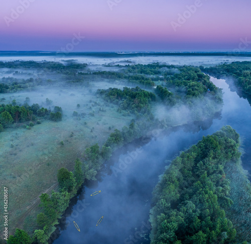 Smoky morning mist over the river. Beautiful panoramic view of river and green banks of the river in the early summer morning. © volff