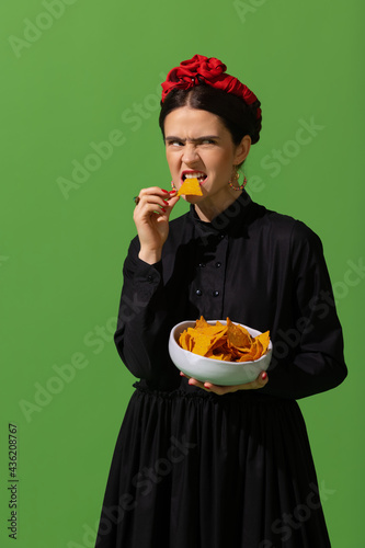 Young woman in art action remaking greatest paintings on green background. Retro style, comparison of eras concept. photo