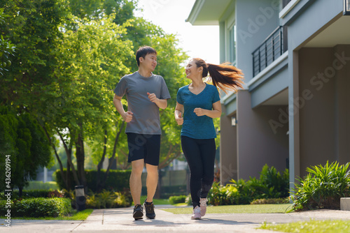 Fototapeta Naklejka Na Ścianę i Meble -  Asian couple are jogging in the neighborhood for daily health and well being, both physical and mental and simple antidote to daily stresses and to socialize safely..