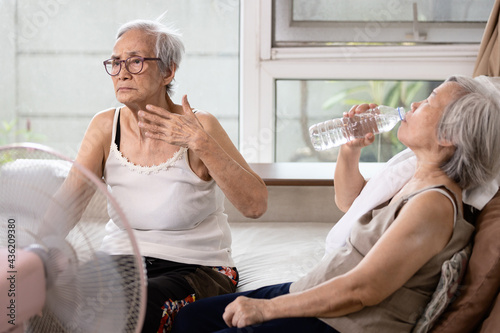 Asian elderly people who are hot and thirsty from high temperature heat waves,drinking water help to reduce body heat,prevent heat stroke,cooling herself in summer hot weather,health care concept photo