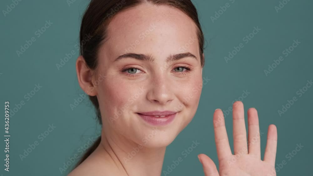 A friendly halfnaked woman is doing hello gesture standing isolated over grey wall in the studio A friendly halfnaked woman is doing hello gesture standing isolated over grey wall in the studio