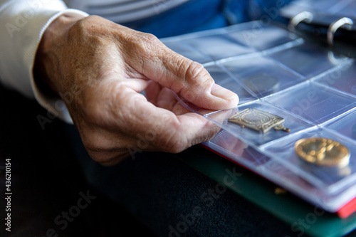 East Sussex, Close-up of senior mans hand holding coin album photo