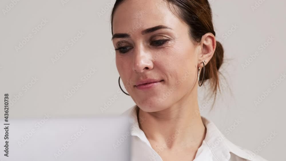 A close-up view of a focused business woman wearing shirt is using her laptop computer sitting in the apartments A close-up view of a focused business woman wearing shirt is using her laptop computer sitting in the apartments