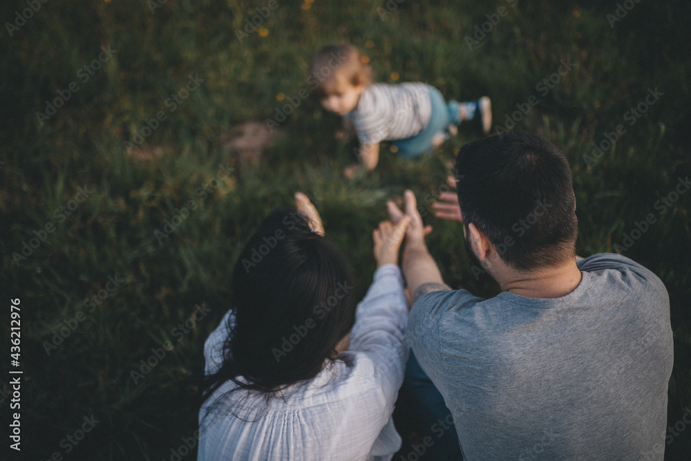 Happy family with a child spends their leisure time in nature, little child crawls away from her parents. Happy family with a child spends their leisure time in nature, little child crawls away from her parents.