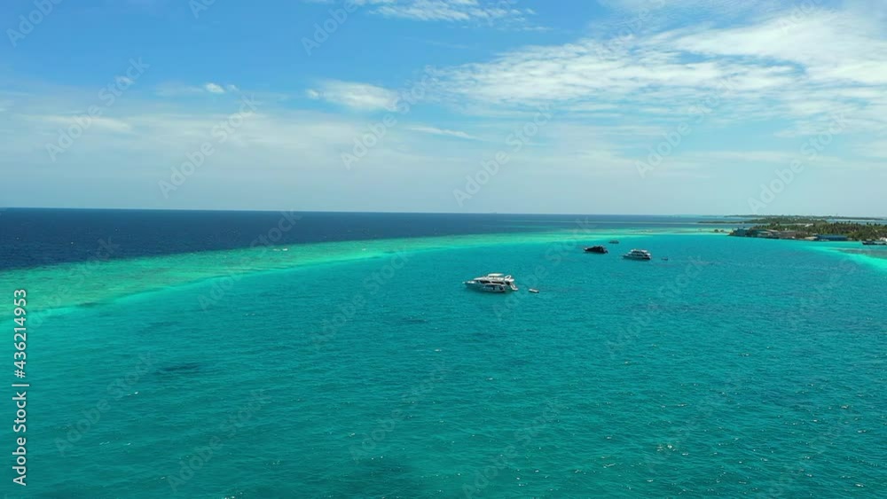 Aerial Panning A Handful Of Boats Moored In A Tropical Harbor Ringed By A Coral Reef With Small Islands In The Distance - Lankanfushi, Maldives Aerial Panning A Handful Of Boats Moored In A Tropical Harbor Ringed By A Coral Reef With Small Islands In The Distance - Lankanfushi, Maldives