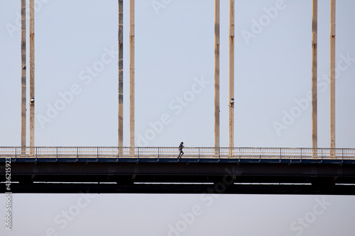 Minimalistic view of a woman running on a bridge in Nijmegen, seen from the side