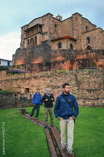 Three young men posing at the Temple of the Sun of the Incas or Coricancha (Qorikancha) in Cusco city, Peru, South America. Traveling friends photo