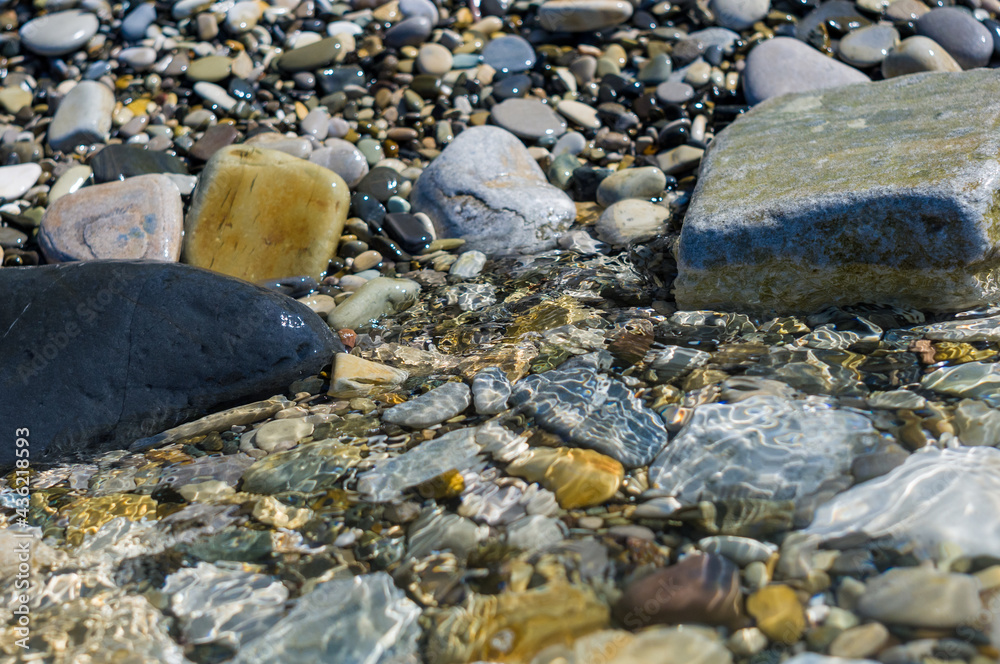 Fototapeta premium pebble stones on the sea beach, the rolling waves of the sea with foam