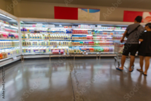 Defocused blur of male and female cart buying milk in supermarket