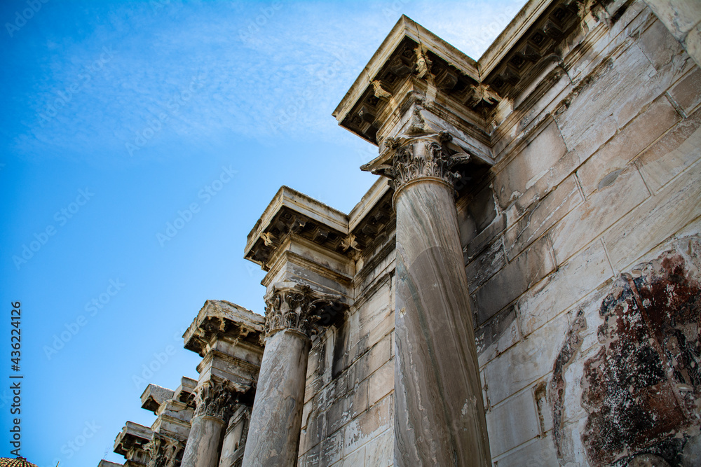 Wall of the ancient Hadrian Library with tall columns against blue sky   in Athens, Greece