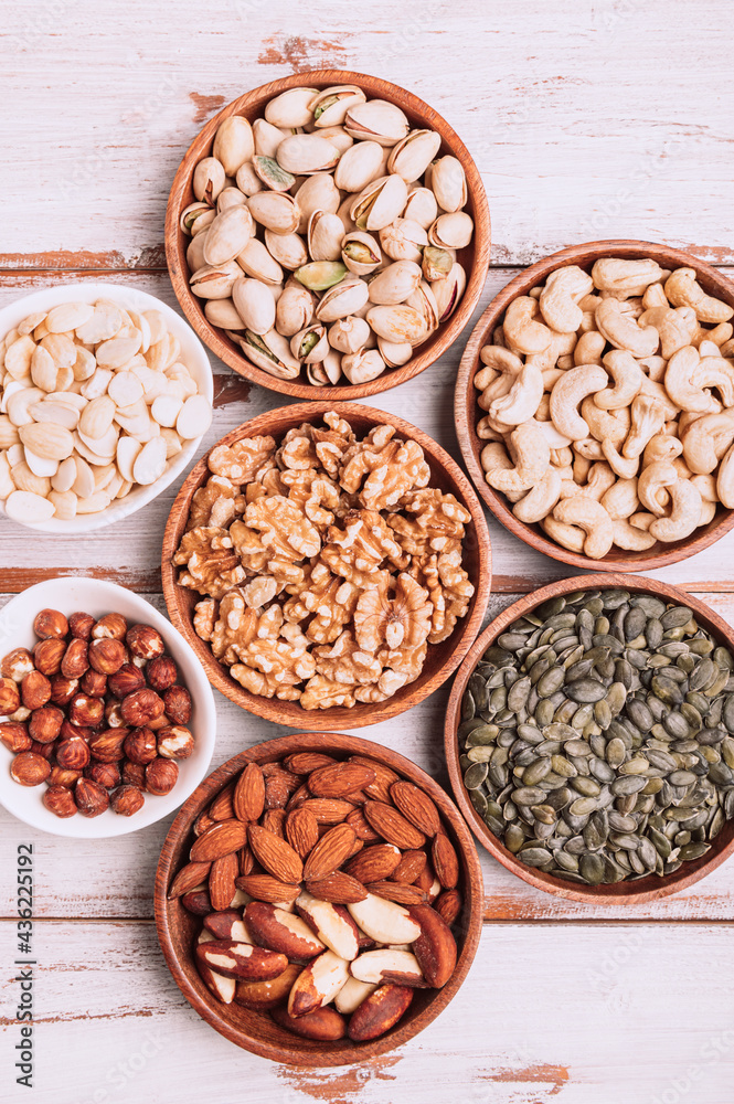 Different kind of nuts in wooden bowls Different kind of nuts in wooden bowls