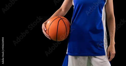 Composition of midsection of female basketball player with ball and copy space on black background © vectorfusionart