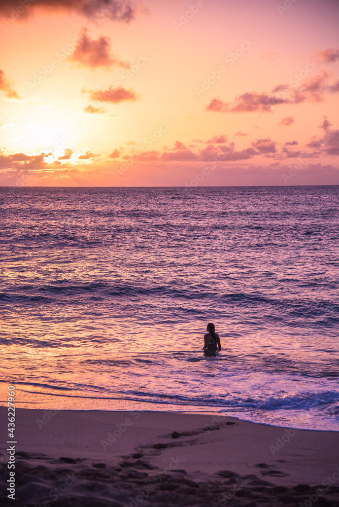 Woman in the ocean on vacation swimming at sunset