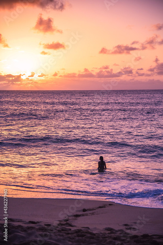 Woman in the ocean on vacation swimming at sunset