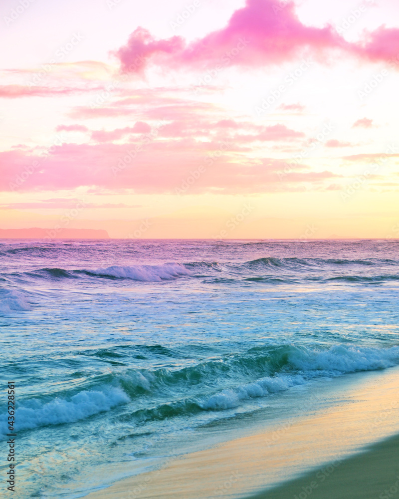 Rainbow color sunset skies at the beach with ocean waves