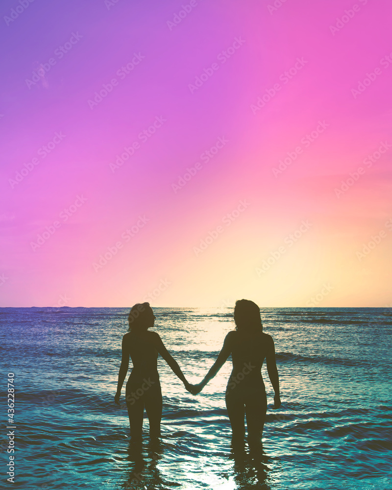 Two friends holding hands at the beach at sunset in the ocean