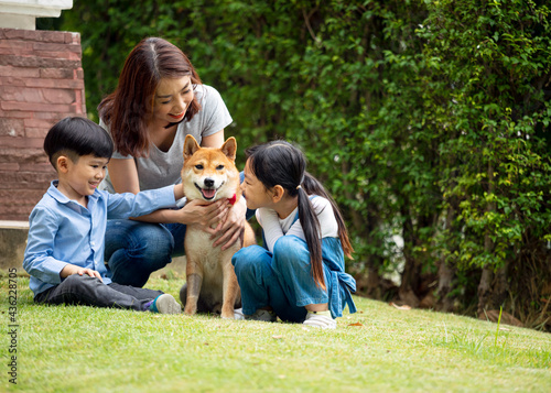 Tableau sur toile Asian mother and two kids sitting and playing together with Shiba inu dog in public park