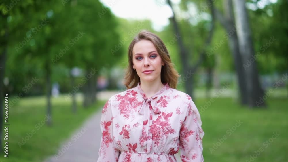 Attractive young woman with smoky eyes make up look at camera smile stand in the city park slow motion Attractive young woman with smoky eyes make up look at camera smile stand in the city park slow motion
