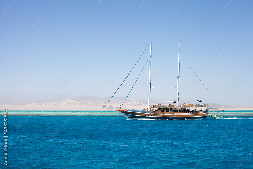 Imitation of a pirate ship with lowered sails, pleasure boat, Red sea and Sinai mountains on a background. Boat trips and sightseeing in Egypt, Sharm el-Sheikh. Travel and tourism concept. Imitation of a pirate ship with lowered sails, pleasure boat, Red sea and Sinai mountains on a background. Boat trips and sightseeing in Egypt, Sharm el-Sheikh. Travel and tourism concept.