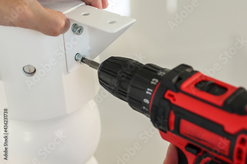 Wallpaper Mural man assembling white table furniture at home using cordless screwdriver Torontodigital.ca