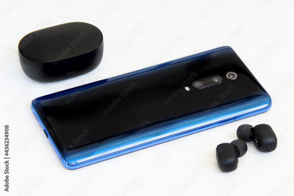 Blue phone with wireless headphones on white background