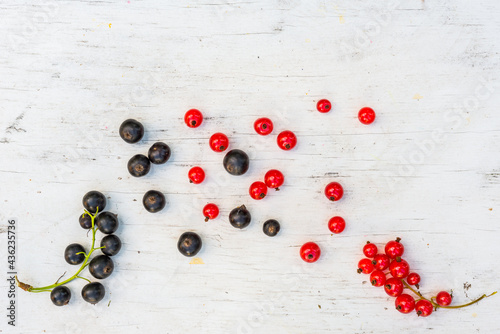 Berries red and black currants are scattered on the old wooden table