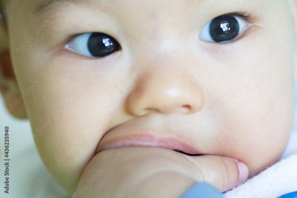 Asia Portrait of a cute baby, (newborn anima) bites hand.The very happy facial expression and emotions child put his fingers in his mouth. Asia Portrait of a cute baby, (newborn anima) bites hand.The very happy facial expression and emotions child put his fingers in his mouth.