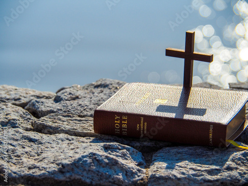 Close up holy bible on stone with bokeh morning light blue sea. Concept Love bible study. Book of life. Old and New Testament. Bible verse Christians Pray Catholic background. Easter, Jesus alive.